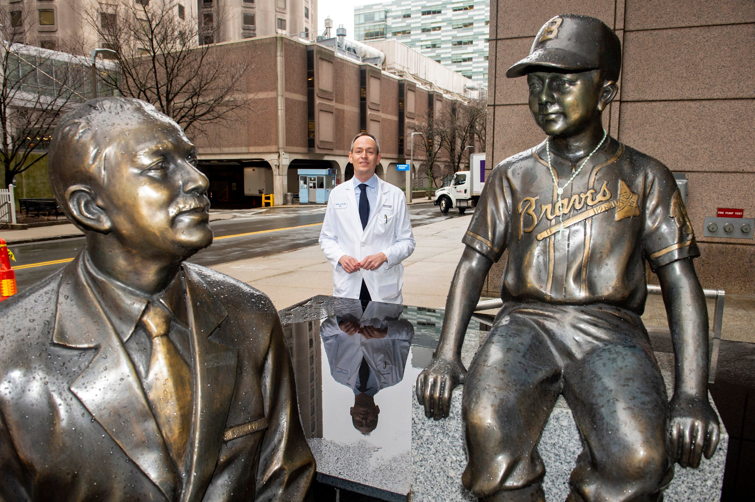 Patrick Ott, Associate Prof of Medicine at HMS and DFCI, stands by the statues of Dana-Farber founder Sidney Farber.