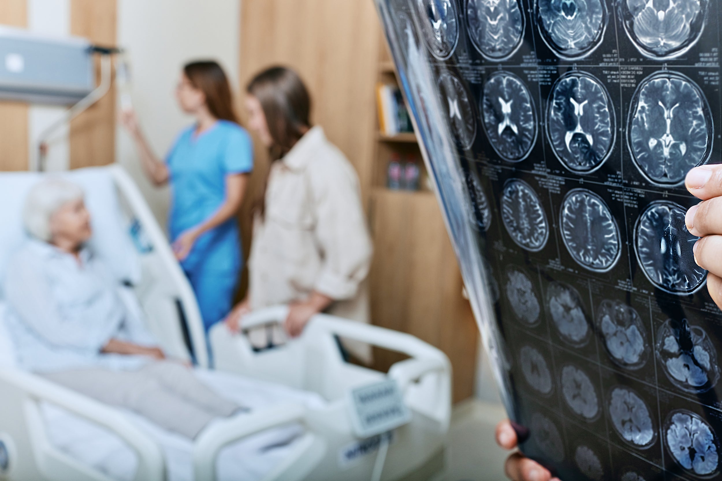 Doctor looks at brain scans with patient in background.